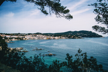 Landscape of the sea and a seaside village framed by some vegetation