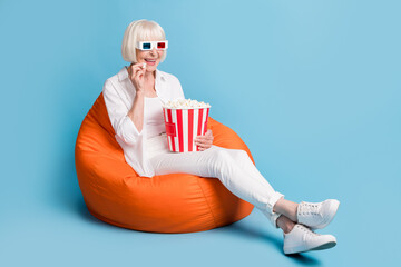 Full length body size photo of old lady in cinema eating pop corn wearing 3d glasses isolated on...