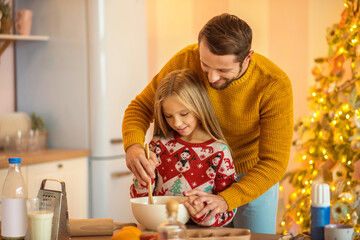 Girl and her dad stirring something in a bowl