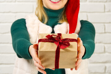 Female hands holding a small gift box wrapped in packing paper. To give and receive gifts from loved ones for christmas, valentines, birthday.
