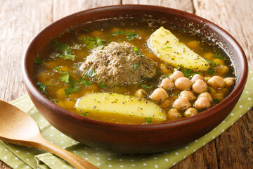 Kufta bozbash soup made from lamb meat balls, chickpeas, potatoes and herbs close-up in a plate. horizontal
