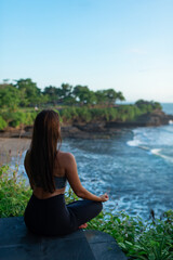 Naklejka na ściany i meble A young woman meditates by the sea.