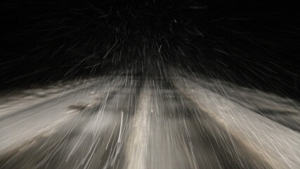 Heavy snowfall, snowstorm on a winter road at night, a car driving on a white highway track with...