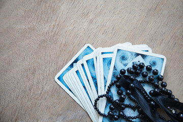 Tarot card deck and black beads necklace for fortune-telling on old wooden table. Foretell the future. Selective focus. Copy space