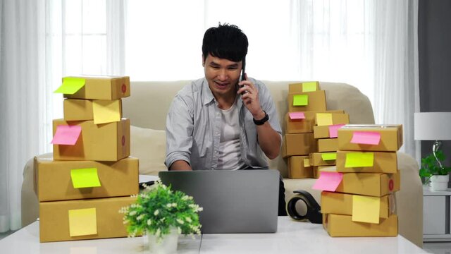 happy man entrepreneur talking on a smartphone and using laptop computer to selling product online at home office, (SME business)