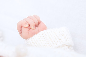 Newborn hand baby in cotton 
blouse on white background