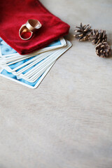Tarot card deck with two golden rings for fortune-telling on old wooden table. Selective focus. Pine cones. Copy space