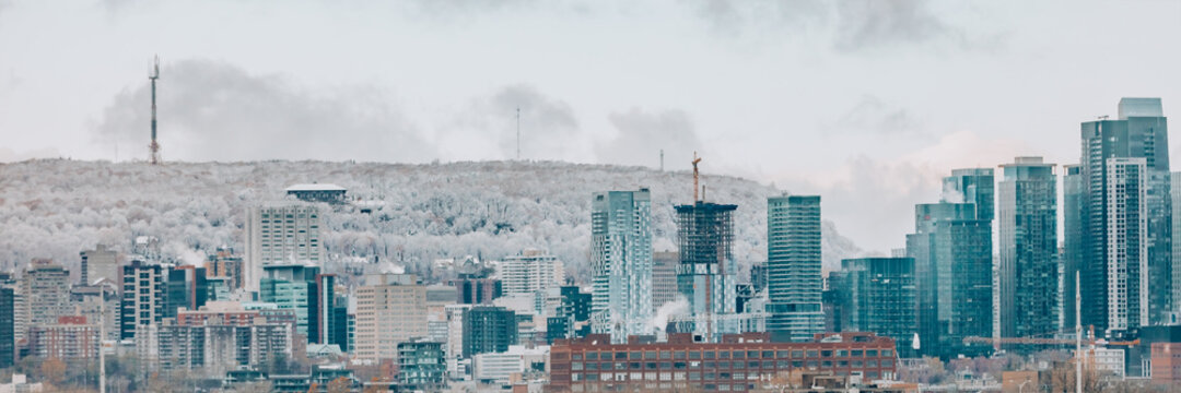 Montreal downtown skyline in winter banner. Panoramic of canadian city with frosted Mount Royal in the background. Construction of condo towers.