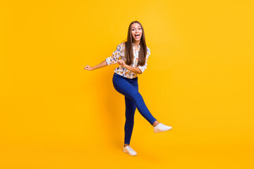 Fototapeta na wymiar Full length photo portrait of funky girl dancing kicking standing on one leg isolated on vivid yellow colored background