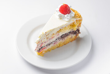 Piece of vanilla and chocolate cake with icing on white isolated background. Served on a white plate.