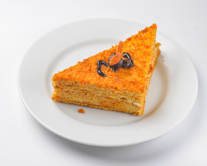 Piece of vanilla and honey cake with icing on white isolated background. Served on a white plate.