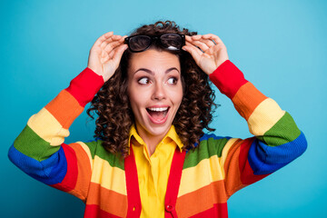 Close-up portrait of pretty cheerful amazed wavy-haired girl touching specs looking aside isolated...