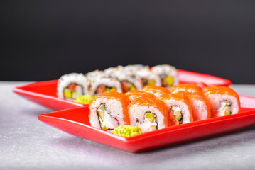 Various kind of sushi food served in red plated over black background. Traditional Japanese cuisine.
