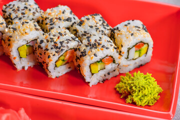 Various kind of sushi food served in red plated over black background. Traditional Japanese cuisine.