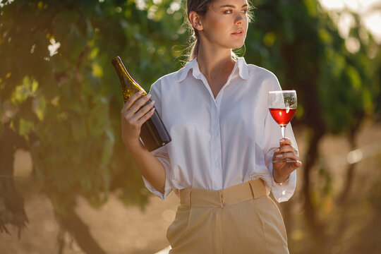Vintner woman tasting red wine from a glass in a vineyard