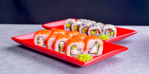 Various kind of sushi food served in red plated over black background. Traditional Japanese cuisine.