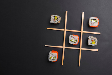 Tic tac toe game with sushi on dark black background, creative concept sushi rolls. Banner, playing tic tac toe game.