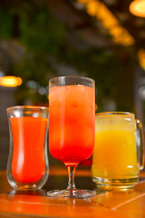 Three cocktails drinks on wooden table at bar indoors. Delicious fruit drinks for refreshment. Alcohol beverage.