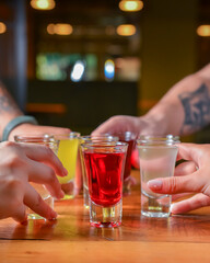 Group of attractive young people toasting with delicious alcohol fruit drinks. Natural berry tincture in shots.