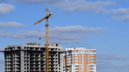 Fototapeta na wymiar Construction crane jib and unfinished multistory building with clouds in sky