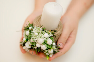 Christmas candles and decorations on a white background. Handmade candlestick. Advent decoration on the boy's hands.