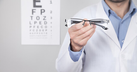 Caucasian professional doctor showing eyeglasses.