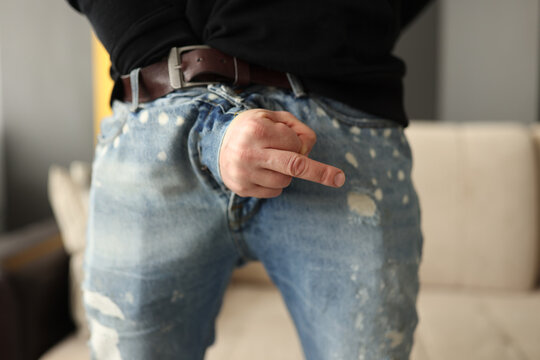 Man showing middle finger from fly of jeans close-up. Potency problems concept