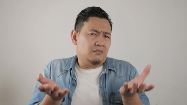 Young Asian man with shrug shoulder up gesture, showing i don't know or rejection