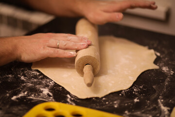 cook rolls out the dough, men's hands work with the dough, cooking dough for dumplings, cook's...