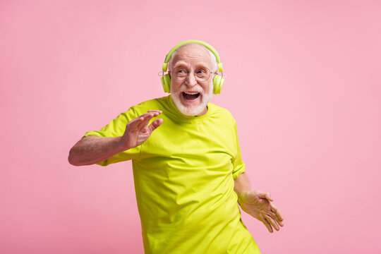 Photo of crazy old man listen music dance wear headphones spectacles lime clothes isolated on pastel pink background