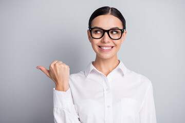 Photo of cute woman indicate thumb look empty space toothy smile wear white shirt isolated grey color background