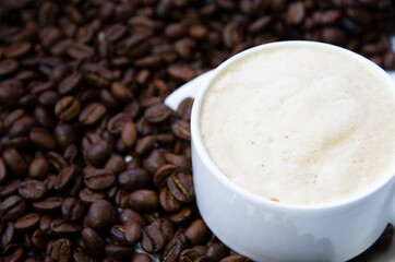 Close-up of coffee cup with roasted coffee beans surrounded by coffee beans