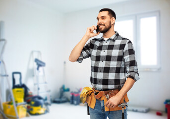 construction, communication and repair concept - happy smiling worker or builder calling on smartphone over room with building equipment background