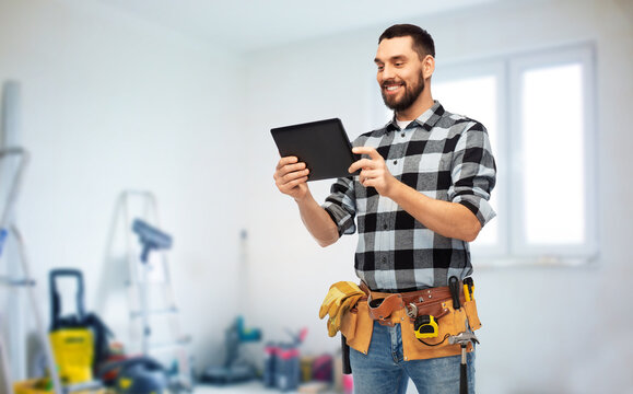 technology, construction and repair concept - happy smiling worker or builder with tablet pc computer and tools over room with building equipment background