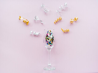 Champagne glasses with confetti and serpentine on a pink background. Flat lay, top view celebrate party concept. New year holiday composition