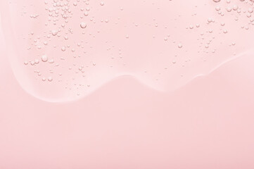 The texture of the gel, skincare serum on a pink background. A transparent liquid cosmetic with...
