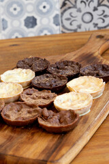 Chocolate coated hazelnut and rice florentines on wood chopping board.  White, milk and dark chocolate selection