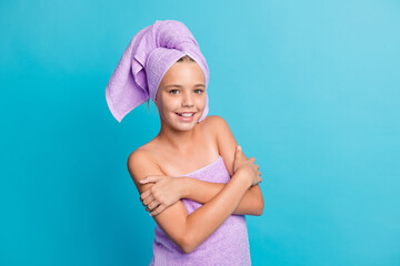 Photo portrait of small girl in bathroom in towel turban embracing hugging herself isolated on vibrant blue color background