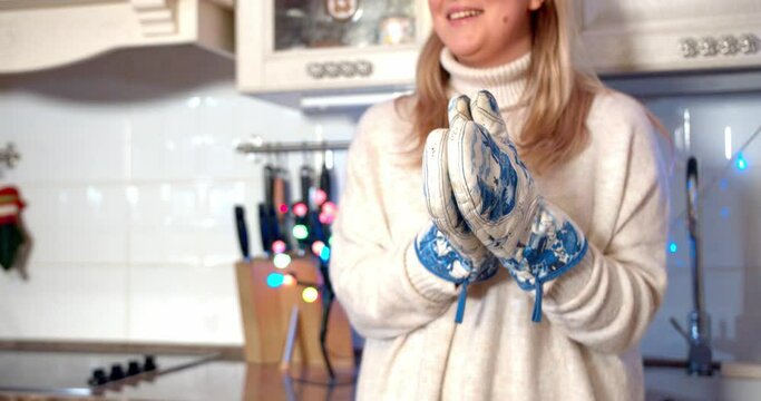 Close up shot of pretty girl claps potholders and laughing in slow motion. Celebrating new year and christmas 2021 at home during covid-19 coronavirus pandemic quarantine concept.