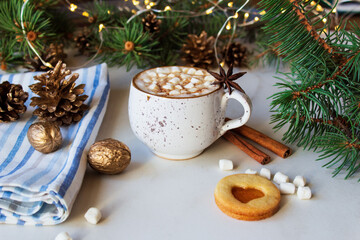 A cup of hot chocolate with marshmallows and linzer cookie on a light background.