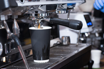 In a cozy coffee shop, the coffee machine prepares delicious aromatic coffee