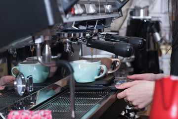 Fototapeta na wymiar Barista girl makes coffee in a coffee machine in a coffee shop