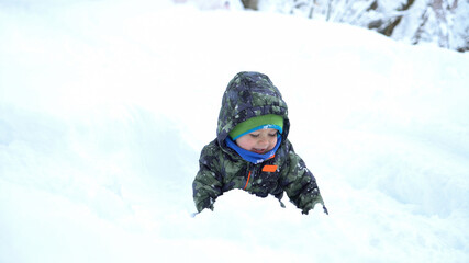 Fototapeta na wymiar Baby boy playing snowballs at snowy winter day