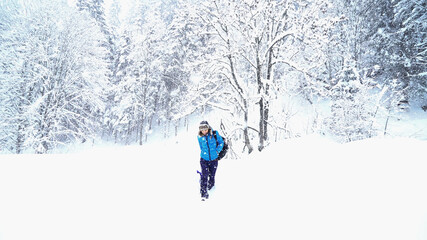 Woman with a sled goes alone along a snow covered winter forest
