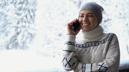 Fototapeta na wymiar Attractive woman talking on cellphone in the snowy forest