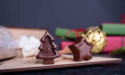 A wooden box gift with a marshmallows for coffee and spoons with chocolates in the form of a star Christmas tree. New Year's content.