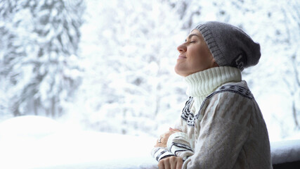 Young happy woman outdoor on the balcony breathing in winter forest 
