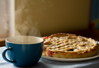 Halloween or Thanksgiving sour cherry pie with pretty lattice top decorated and a tea or coffee cup. Classic recipe, view from above. Homemade Cherry Pie with a Flaky Crust on blue napkin background
