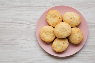 Homemade Flaky Buttermilk Biscuits on a pink plate on a white wooden background, top view. Flat lay, overhead, from above. Copy space.