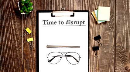 Paper with TIME TO DISRUPT on charts on wooden background
